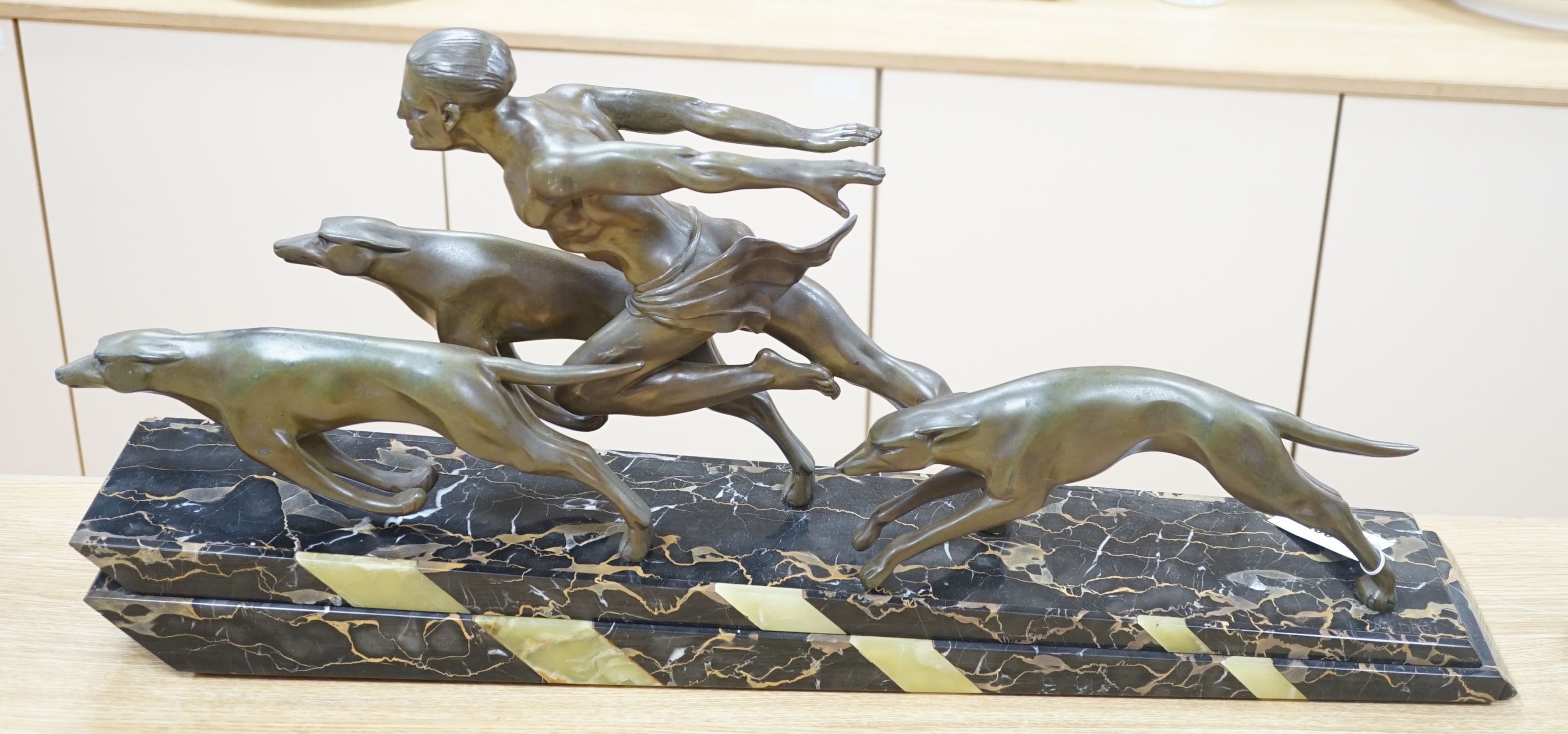 An Art Deco bronzed metal and marble running man with greyhounds, signed L Valderi, 85cm long